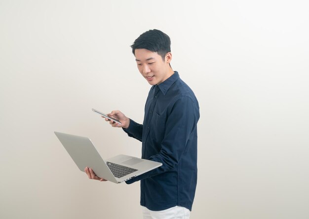 portrait young Asian man talking smartphone or mobile phone and hand holding laptop on white background