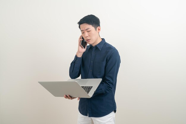 portrait young Asian man talking smartphone or mobile phone and hand holding laptop on white background