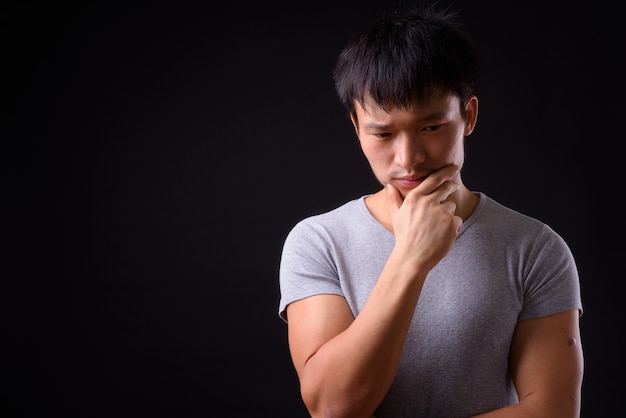 Portrait of young Asian man thinking and looking away