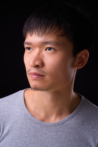 Portrait of young Asian man thinking and looking away