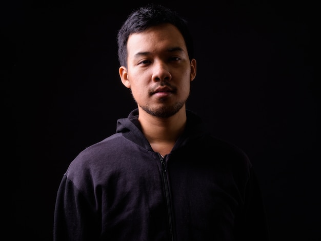 portrait of young Asian man wearing hoodie on black