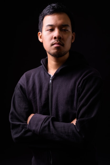 portrait of young Asian man wearing hoodie on black