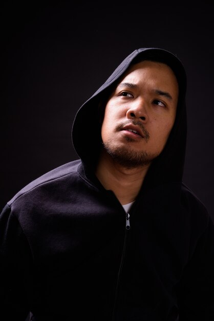 portrait of young Asian man wearing hoodie on black