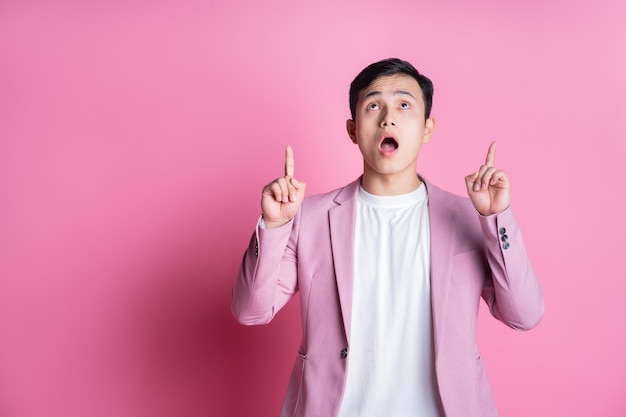 Portrait of young Asian man wearing pink suit posing on background