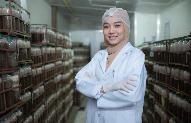 Portrait of young asian muslim female scientist doing research at a mushroom factory examining mushroom leavening agent in a sterile and temperaturecontrolled room