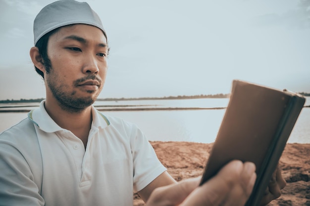 Portrait of Young asian muslim man praying on sunsetRamadan festival conceptReading a book