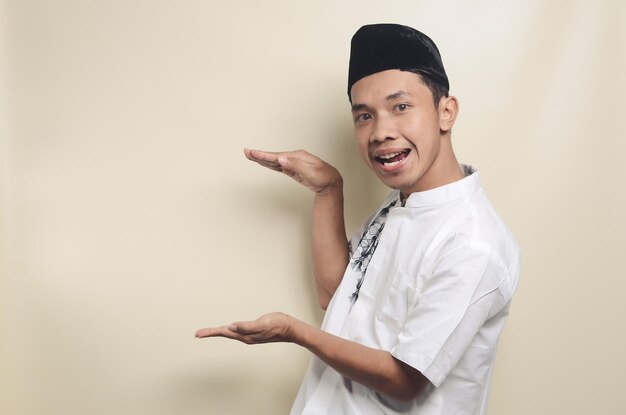 Portrait of young Asian Muslim man showing big size with his hands isolated background