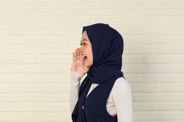 Portrait of young Asian muslim woman wearing hijab shouting and yelling