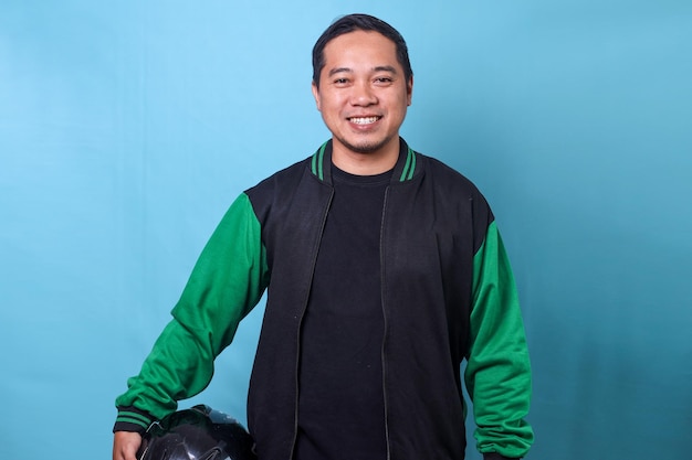 Portrait of young Asian online driver man holding helmet and wearing uniform jacket while looking at