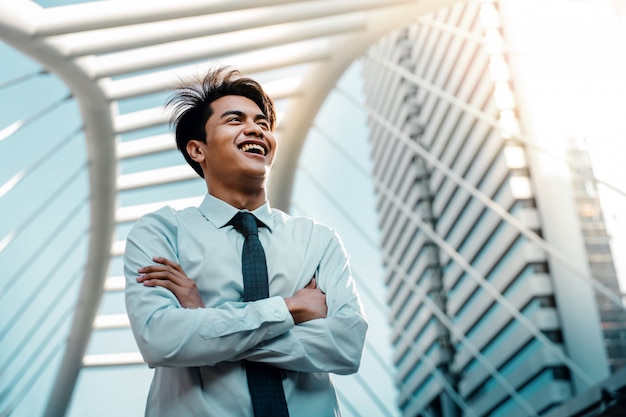 Portrait of a Young Asian Smiling Businessman in the City. Crossed Arms and looking away