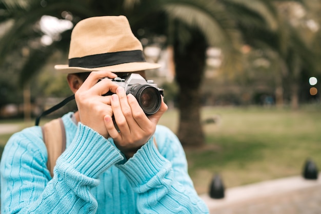 ヴィンテージカメラと屋外の通りでいくつかの写真を撮る若いアジア人観光客の肖像画。旅行のコンセプト。