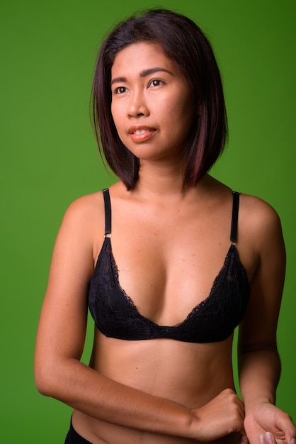 Portrait of young Asian woman against green wall