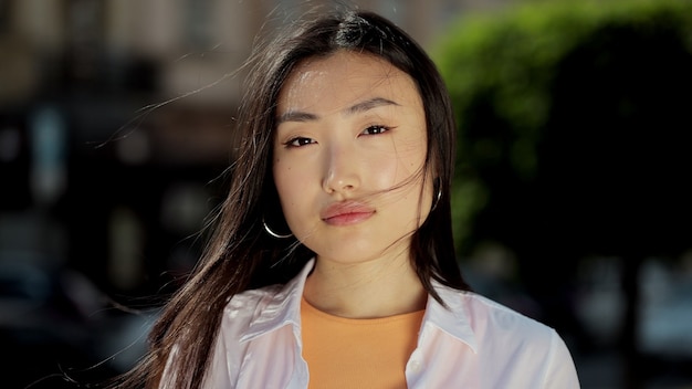 Portrait of a young asian woman in casually dressed looking to camera outside on street closeup face of beautiful asian girl stand in the city streets summer beautiful lady portrait happy outdoor