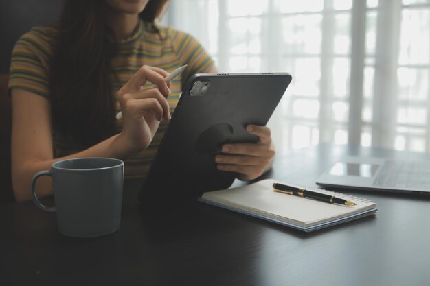 Portrait of Young Asian woman hand freelancer is working her job on computer tablet in modern office Doing accounting analysis report real estate investment data Financial and tax systems concept