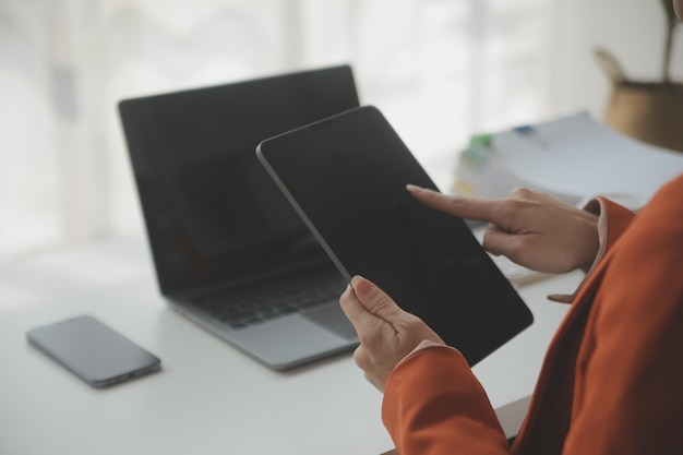 Photo portrait of young asian woman hand freelancer is working her job on computer tablet in modern office doing accounting analysis report real estate investment data financial and tax systems concept