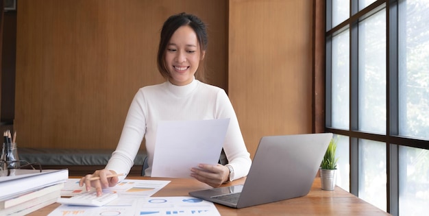 Portrait of young asian woman hand freelancer is working her\
job on computer tablet in modern office doing accounting analysis\
report real estate investment data financial and tax systems\
concept