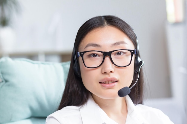 Portrait of a young asian woman in headphones with a microphone works as a consultant in a call