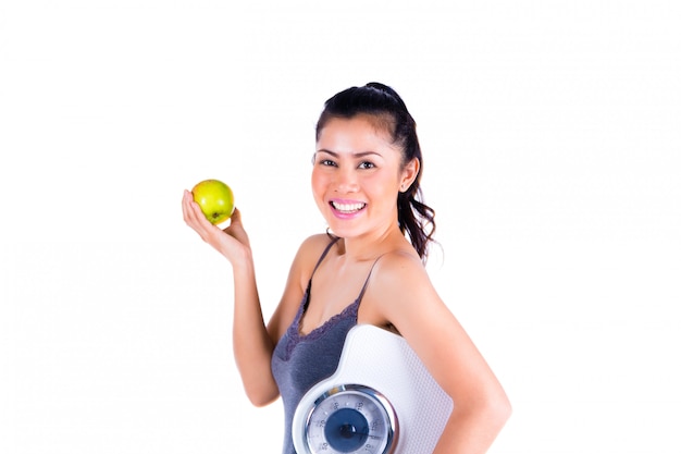 Portrait of young Asian woman holding apple and scale