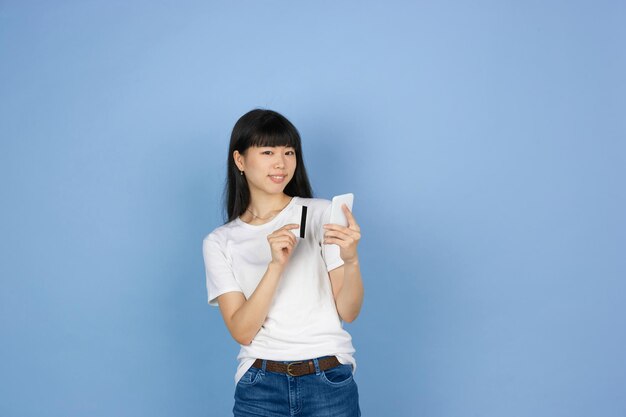 Ritratto di giovane donna asiatica isolata sul fondo blu dello studio