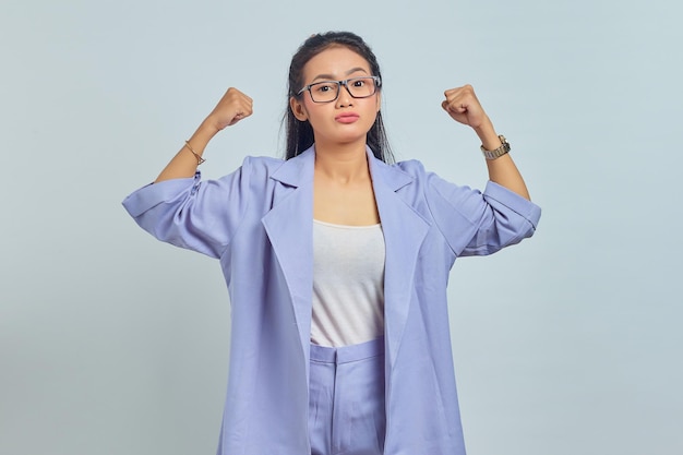 Portrait of young Asian woman raising hands and showing biceps isolated on white background
