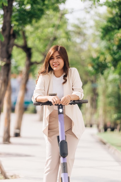 Portrait of young asian woman riding electric scooter in park