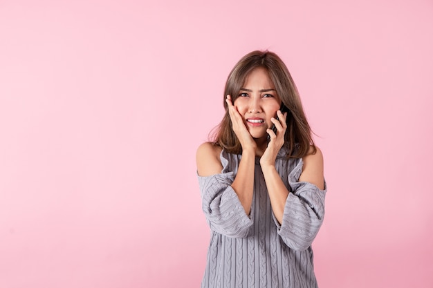 Portrait of a young Asian woman shocked by the bad news heard from a smartphone