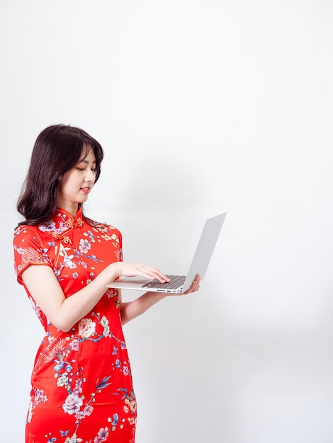 Portrait of a young asian woman in traditional cheongsam qipao dress using laptop on white background