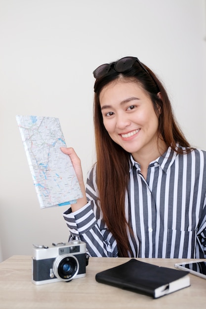 Portrait of young asian woman traveler holding map with smiling, travel holiday vacation c