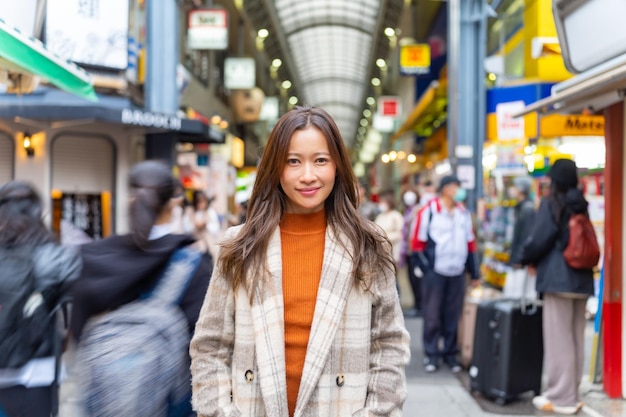 秋の東京市の街頭市場で歩き買い物をしている若いアジア人女性の肖像画 魅力的な女の子が冬休みの休暇で都市での楽しい都市的なアウトドアライフスタイル旅行を楽しんでいます