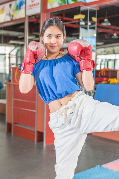 portrait of young asian woman wearing boxing gloves practising boxing in gym.