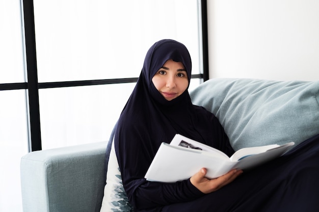 Hijab를 입고 젊은 아시아 여자의 초상화, 집에서 책을 읽고
