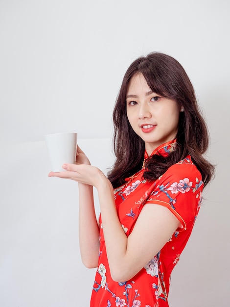 Portrait of young asian woman wearing traditional cheongsam qipao dress relaxing drinking on white background