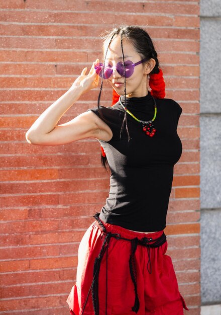 Photo portrait of a young asian woman with colored glasses posing in the street in vertical view