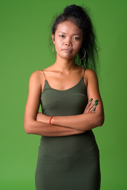 녹색 벽에 곱슬 머리를 가진 젊은 아시아 여자의 초상화