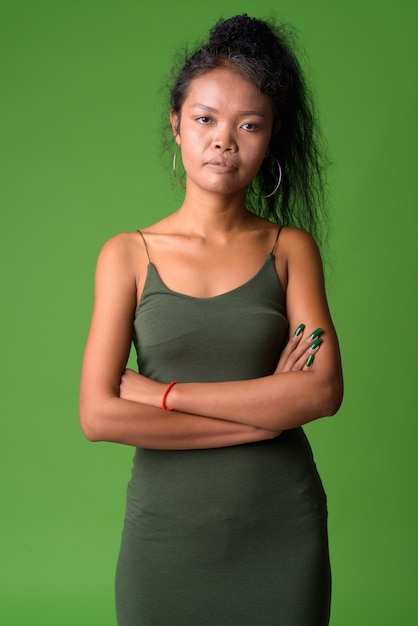 Portrait of young Asian woman with curly hair against green wall