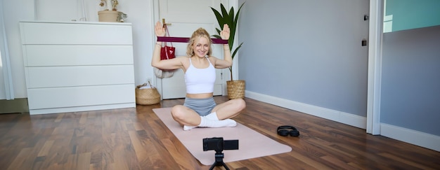 Portrait of young athletic woman recording home workout video shooting content for sport fitness