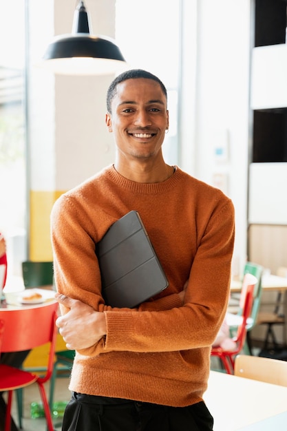 Portrait of young attractive African man holding tablet and looking at camera with smiling face