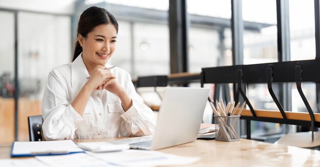 Portrait of young attractive asian woman relaxing while sitting at her office desk