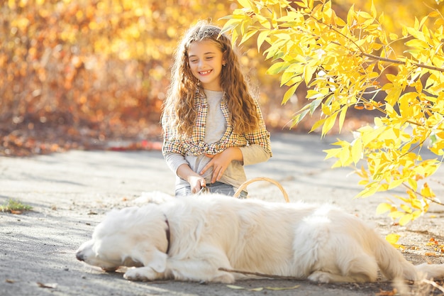 Portrait of young attractive blond girl with dog. Pet owner. Golden retriever and his owner in autumn.