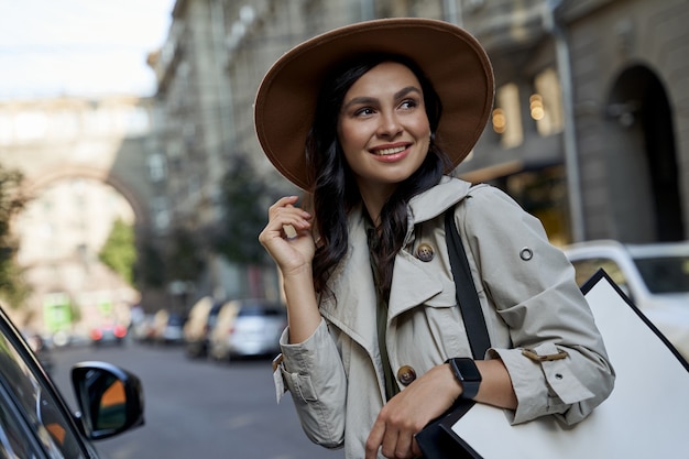 Portrait of a young attractive caucasian woman in hat with shopping bag looking aside and