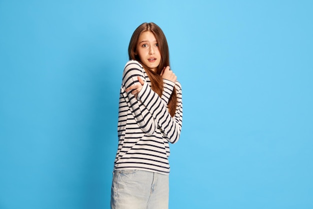 Portrait of young attractive girl in casual clothes hugging herself feeling fear and stress against