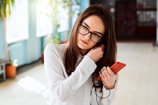 Portrait of young attractive girl in university putting her earphones to the ears