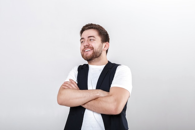 Photo portrait of young attractive smiling brunette man in white shirt on gray background.