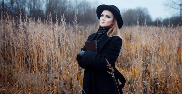 Portrait of young attractive woman in black coat and hat. 