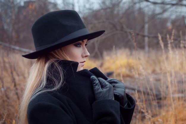 Portrait of young attractive woman in black coat and hat.