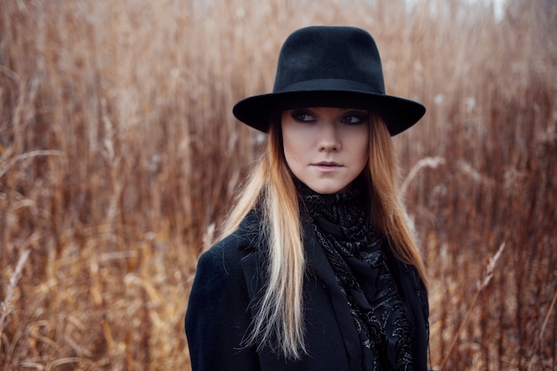 Portrait of young attractive woman in black coat and hat. 