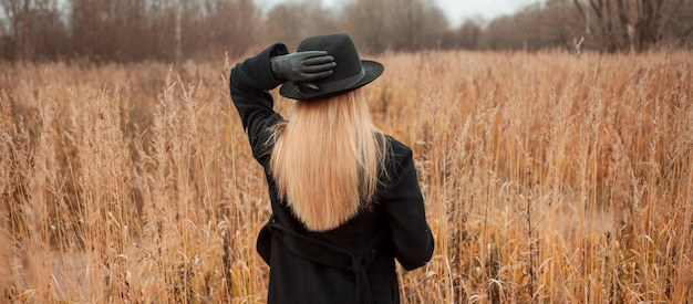 Ritratto di giovane donna attraente in cappotto nero e cappello