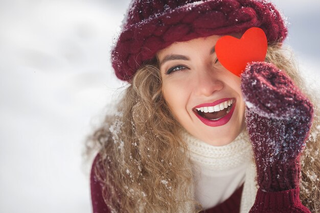 Ritratto di giovane donna attraente all'aperto nell'orario invernale che mostra il cuore di carta