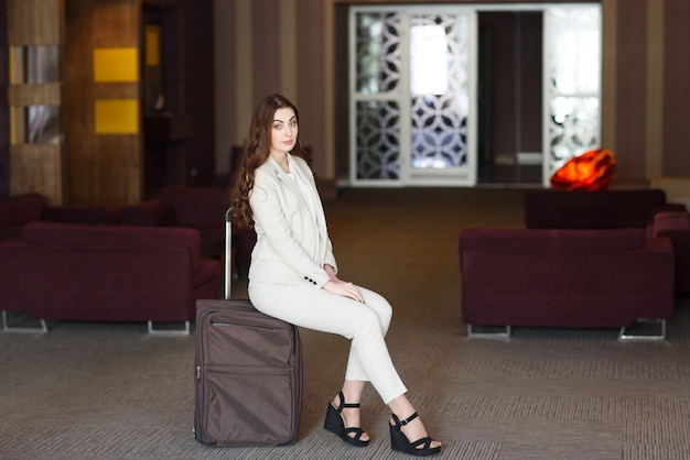 Portrait young attractive woman sitting on suitcases in the terminal or train station. The girl met on a trip.