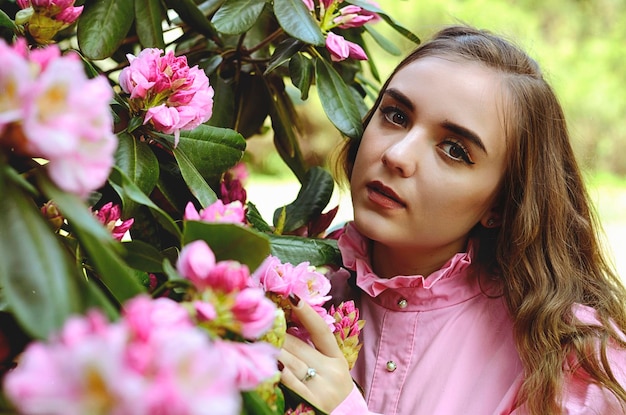 ライラックの花束と春の庭で若い魅力的な女性の肖像画。春の背景。